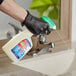 A person in black gloves using Comet All Purpose Cleaner with Bleach to spray a sink.