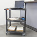 A laptop on a black Luxor utility cart shelf.