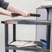 A person using a Luxor black utility cart to hold a laptop.