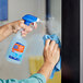 A hand using Spic and Span Disinfecting All-Purpose and Glass Cleaner to spray a window.