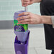 A hand holding a purple Swiffer WetJet Multi-Surface Cleaner Solution container with a green and white label.