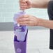 A person holding a purple container with a purple Swiffer WetJet label.