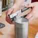 A person using a Swing-A-Way handheld can opener with a black handle to open a can.