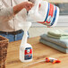 A person pouring Febreze Professional sanitizing liquid into a white bottle.