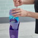 A person's hand holding a purple Swiffer WetJet container.