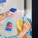 A hand spraying Spic and Span All-Purpose and Glass Cleaner from a bottle onto a window.