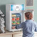 A woman opening the white Avantco countertop freezer.