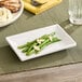 An American Metalcraft white rectangular mini melamine plate with green beans and almonds on it.