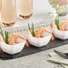 A black tray with small white plastic bowls filled with shrimp and green onions.