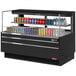 A black Turbo Air horizontal refrigerated curtain merchandiser with cans of soda on a shelf.