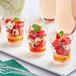 A group of Choice clear plastic tiny shot glasses filled with watermelon and feta salad on a table at a catering event.