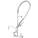 A silver T&S EasyInstall wall mounted pre-rinse faucet with a curved hose.