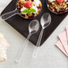 Two clear plastic Visions tasting spoons with dessert.
