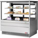 A Turbo Air stainless steel refrigerated bakery display case with flat glass shelves holding cakes and desserts.