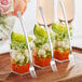 A Visions silver plastic tasting fork next to small containers of food on a table.