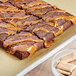 A tray of brownies with caramel topping and nuts on a table in a bakery display.