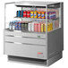 A Turbo Air stainless steel horizontal refrigerated open curtain merchandiser with drinks on a shelf.