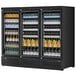 A black Turbo Air refrigerated glass door merchandiser full of bottles of liquid and juice.