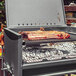 A Nuke BBQ Pampa grill with meat cooking on it.