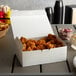 A white take out box of fried chicken on a table.