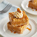 A close up of a caramel dessert with whipped cream on a plate.