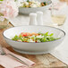 A grey Acopa Embers stoneware bowl filled with pasta on a table with a fork and knife.