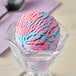A scoop of Oringer Cotton Candy hard serve ice cream in a clear bowl with blue and pink swirls.