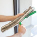 A person using an Unger ErgoTec Ninja window washer to clean a window.