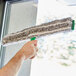 A hand using an Unger ErgoTec Ninja window cleaning brush on a window.