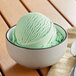 A bowl of green peppermint ice cream with a scoop of Oringer Peppermint Hard Serve Ice Cream Flavoring.