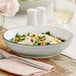 An Acopa Embers stoneware pasta bowl filled with pasta on a table.