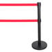 A black Aarco crowd control stanchion with dual red retractable belts.