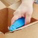 A hand using a blue Klever Kutter Koncept to open a box.