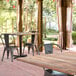 A Lancaster Table & Seating cast iron table base on a brick patio with chairs.