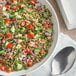 A bowl of salad with tomatoes, cucumbers, and onions with McCormick Guacamole Seasoning on the side.