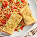 A plate of spaghetti with a piece of bread on it.