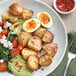 A plate of food with potatoes, avocado, and McCormick Culinary Bacon Flavored Bits on a table.