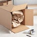 A Lavex Kraft cardboard shipping box with crumpled paper inside.