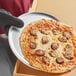 A pizza on a Choice 12" round aluminum tray.