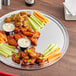 An 18" round aluminum tray with a wide rim holding a plate of carrots and celery.