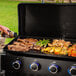 A person cooking food on a Pit Boss 5 burner gas griddle.