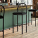 A Lancaster Table & Seating bar stool with a black upholstered seat.