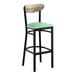 A bar stool with a black metal frame, a seafoam vinyl seat, and a driftwood-finished wooden backrest.