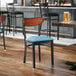 A black metal chair with a blue vinyl seat and an antique walnut wood backrest.