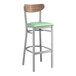 A Lancaster Table & Seating bar stool with a seafoam vinyl seat and wood back.