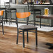 A black metal chair with a dark gray vinyl seat and a cherry wood backrest.