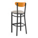 A Lancaster Table & Seating black bar stool with a light gray cushioned seat and cherry wood back.