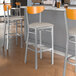 Lancaster Table & Seating Boomerang Series bar stools with light gray vinyl seats and cherry wood backs.