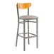A Lancaster Table & Seating bar stool with a cherry wood back and light gray cushion.