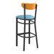 A Lancaster Table & Seating bar stool with a blue vinyl seat and cherry wood back.